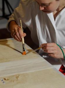 Mit Pinsel und Ministaubsauger werden die kostbaren Seidenfasern von schädigenden Staubauflagen befreit. (c) Foto: Ulrike Reichert